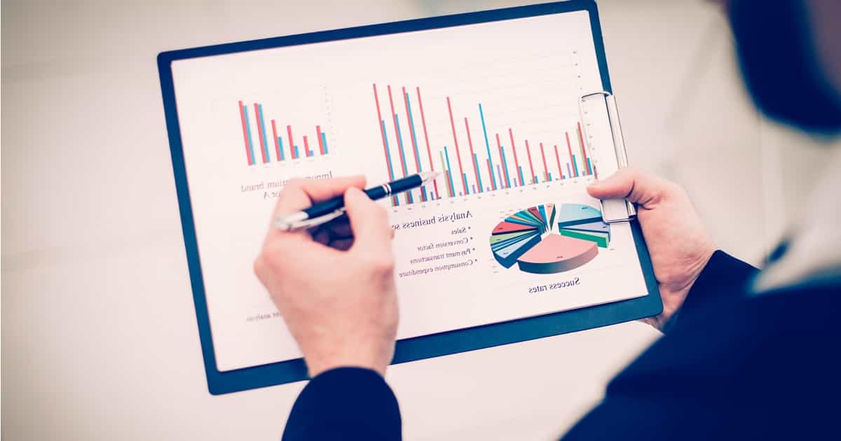 Eine Person analysiert mit einem Stift Finanzdiagramme auf einem Tablet.