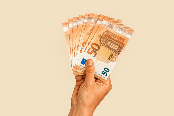 Hand hält Geld vor sandfarbenen Hintergrund