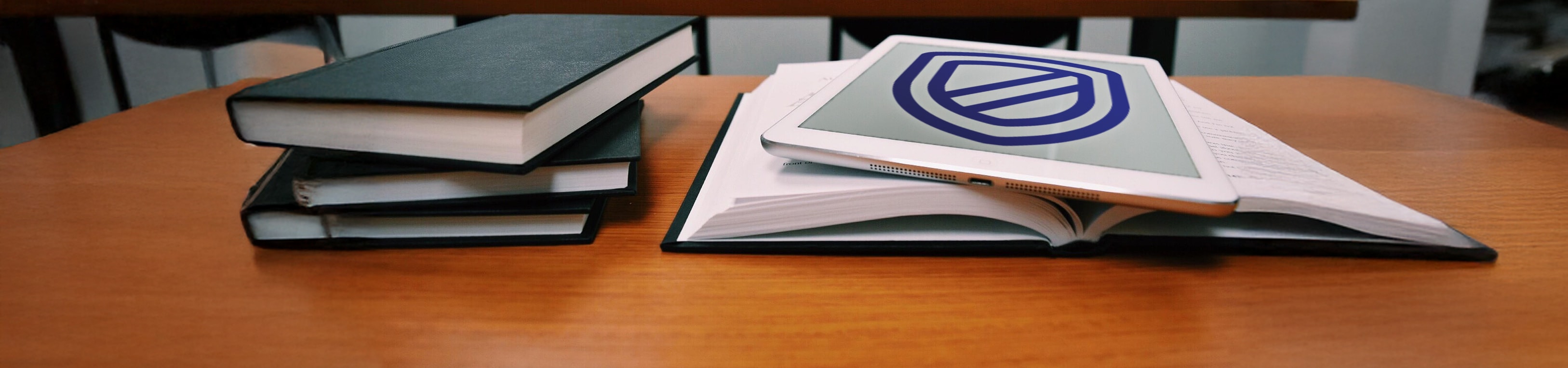 Tablet mit Versicherungsschild liegt im Klassenzimmer neben Büchern