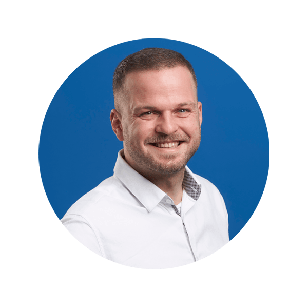 Ein lächelnder Mann in einem weißen Hemd vor einem blauen grafischen Hintergrund.