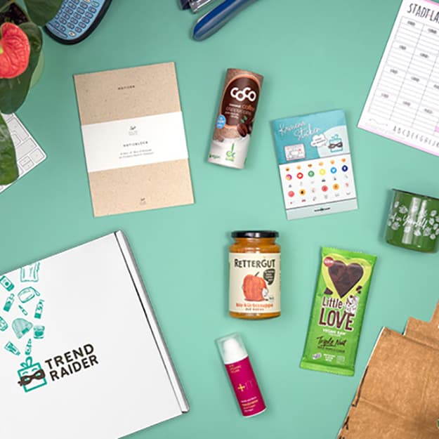 Verschiedene umweltfreundliche Produkte, darunter Snacks, Kosmetika und Schreibwaren auf türkisfarbenem Hintergrund.