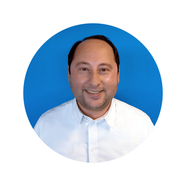 Ein lächelnder Mann in einem weißen Hemd vor blauem Hintergrund.